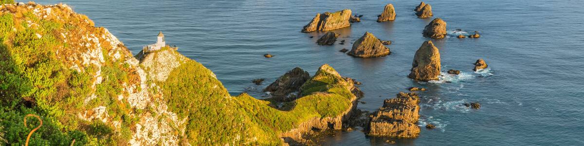 Rainbow over Nugget Point lighthouse after the storm. Ahuriri Flat, Clutha district, Otago region, South Island, New Zealand.