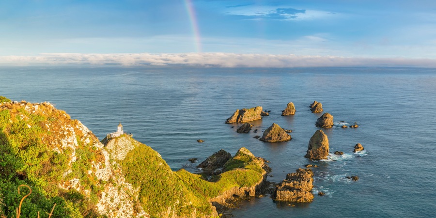 Rainbow over Nugget Point lighthouse after the storm. Ahuriri Flat, Clutha district, Otago region, South Island, New Zealand.