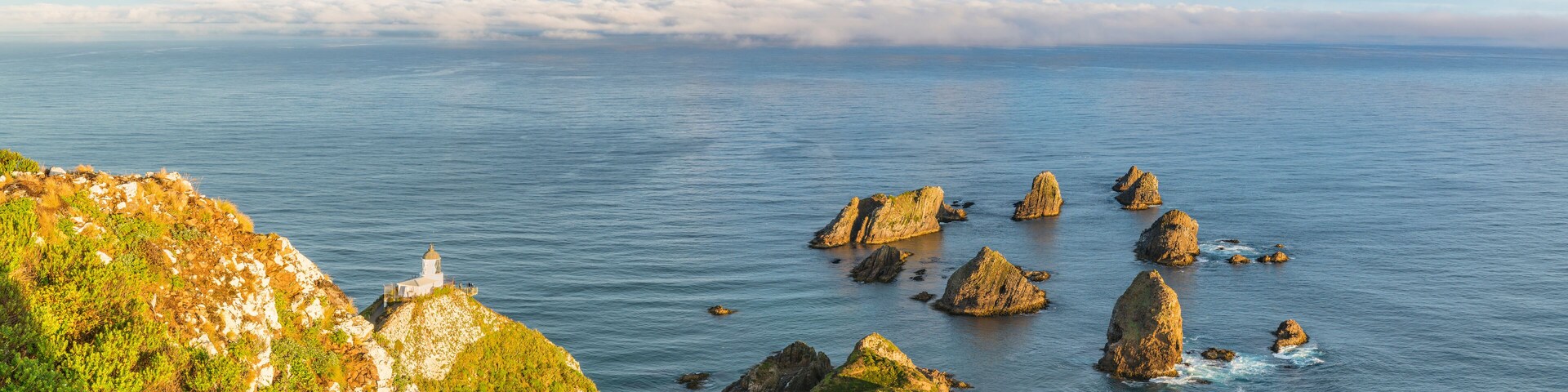 Rainbow over Nugget Point lighthouse after the storm. Ahuriri Flat, Clutha district, Otago region, South Island, New Zealand.