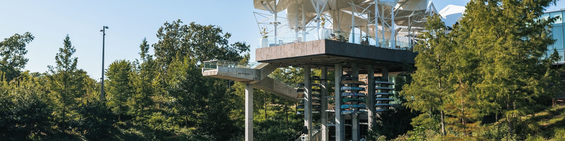 Uma estrutura arquitetônica moderna com design único, localizada à beira de águas tranquilas, cercada por vegetação exuberante.