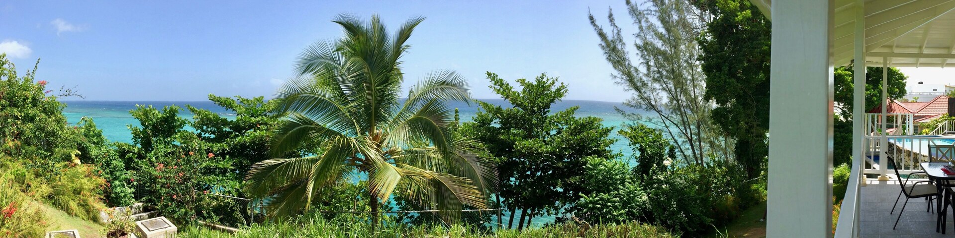 Luxurious tropical resort (hotel) with blue sky, white patio, lush green palm trees & blue ocean in Boscobell near Oracabessa (James Bond beach) on the Caribbean island of Jamaica in the West Indies