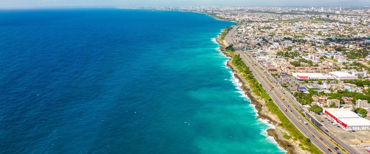 Aerial view of Santo Domingo este. The Autopista Las Americas along the rocky shore of turquoise caribbean sea. Expressway from the Punta Cana to the capital of Dominican Republic