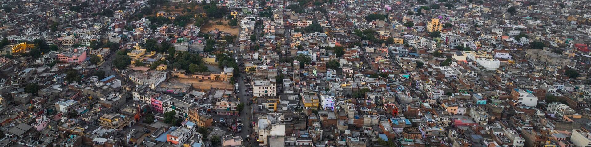 Aerial view of vibrant and bustling cityscape with historic architecture and scenic rooftops amidst hills, Sindhi Camp, Jaipur, India.