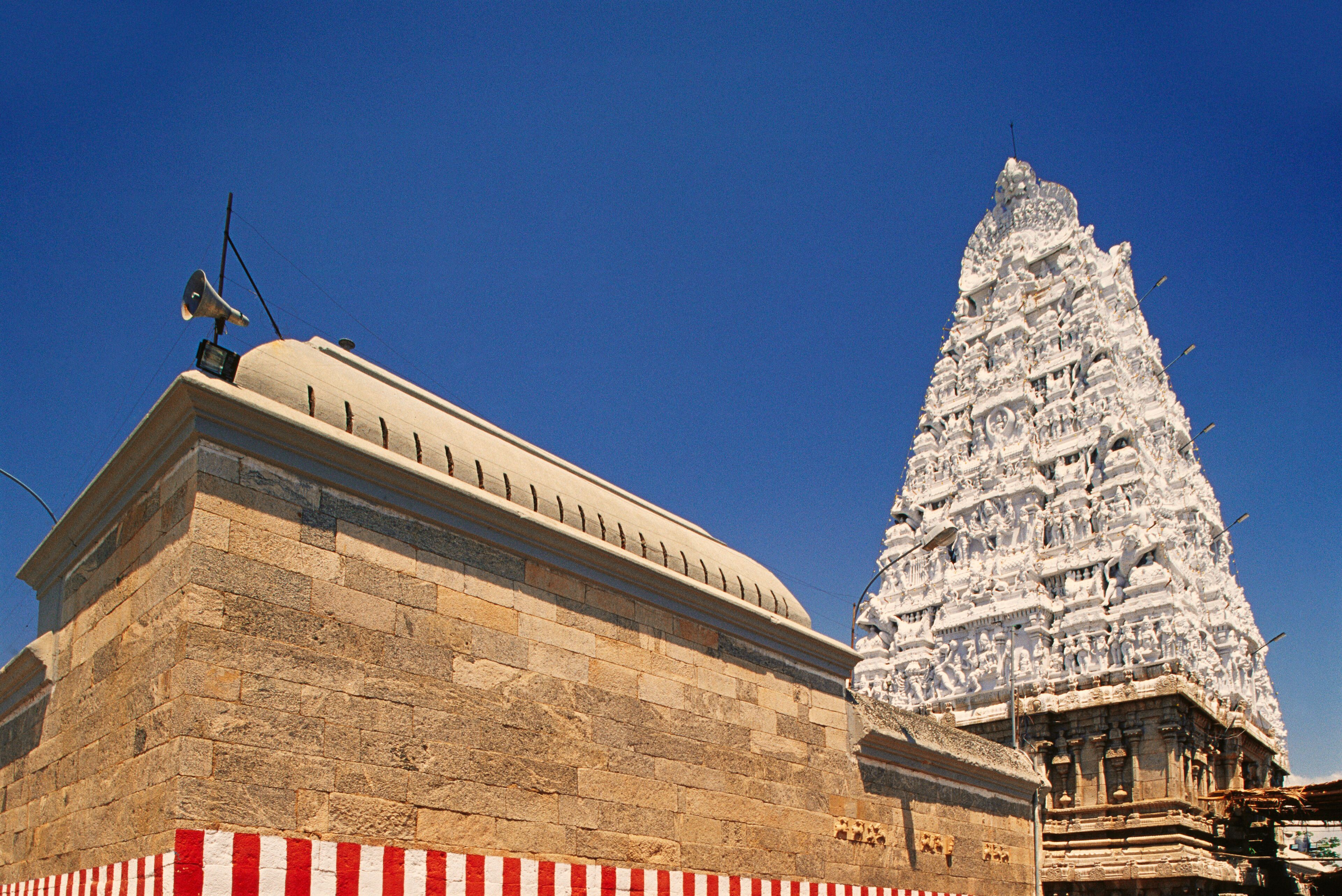 A temple with a large, ornate spire and a stone structure with a striped base.