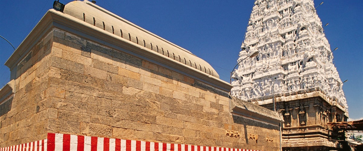 A temple with a large, ornate spire and a stone structure with a striped base.