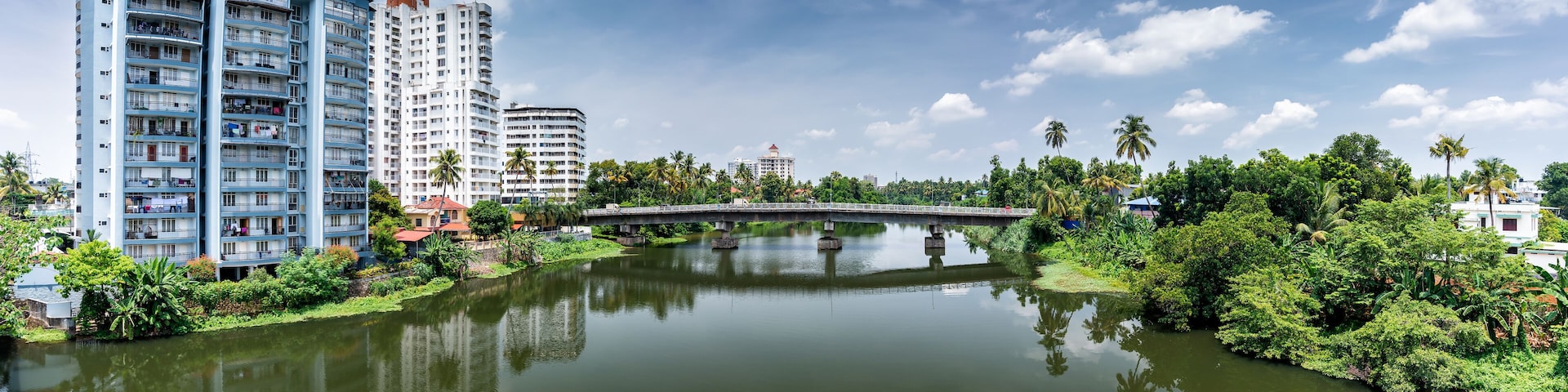 A river with a bridge, surrounded by greenery and tall buildings.
