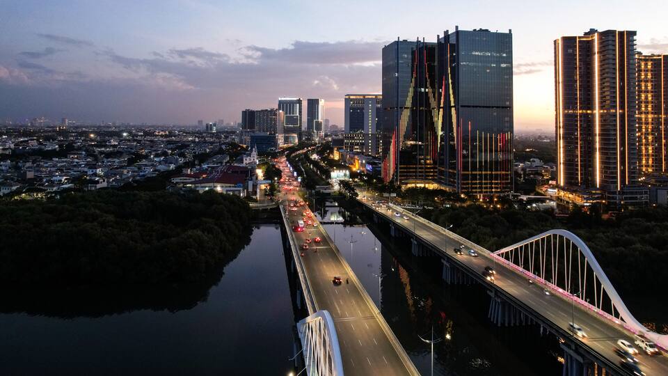 Aerial view of Pantai Indah Kapuk Avenue Bridge Jakarta. a Largest bridge in Jakarta. With Jakarta cityscape and noise cloud when sunset.