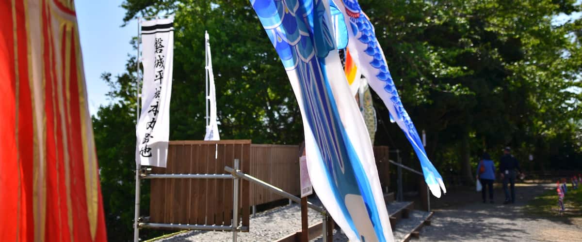 A traditional Japanese sailboat with a blue and white sail, a wooden fence, and a clear blue sky.