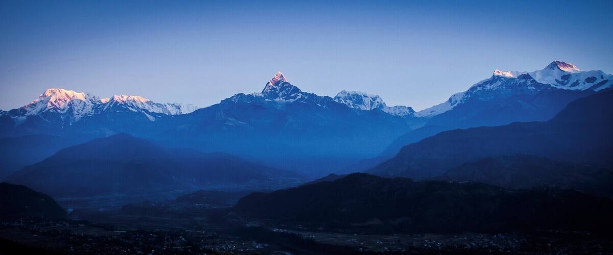 A mountain range with snow-capped peaks and a valley below.