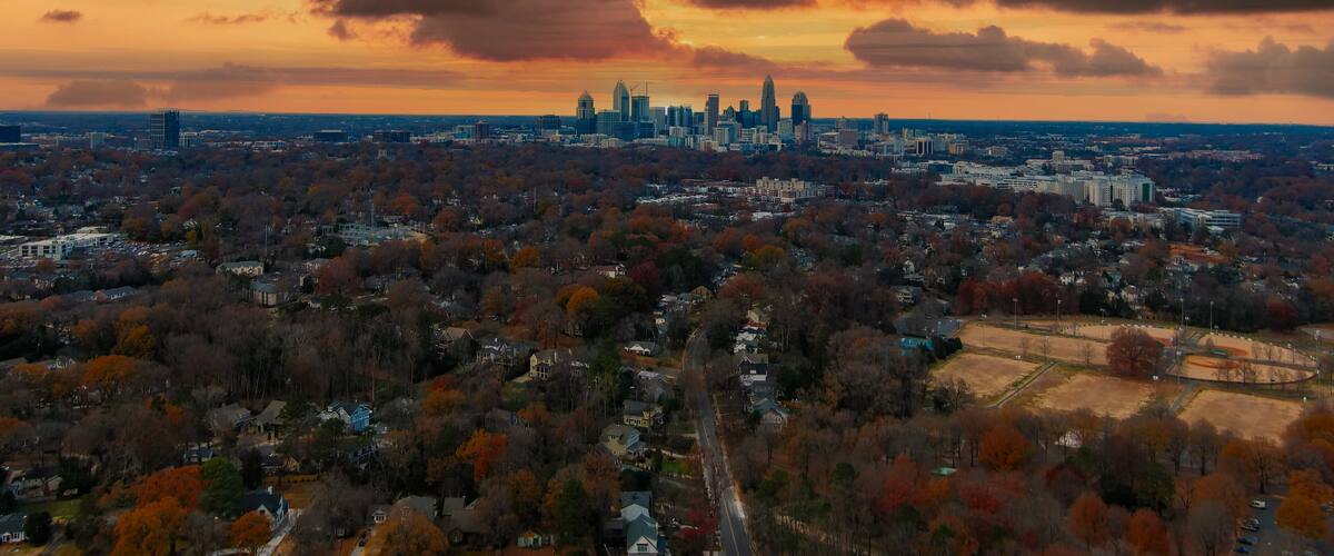 a gorgeous aerial shot of the downtown cityscape with skyscrapers and vast miles of autumn colored trees with red sky and powerful clouds at Freedom Park in Charlotte North Carolina USA