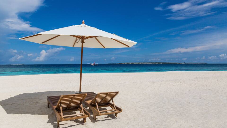 Sonnenschirm und Liegen am Strand Atoll Insel Malediven