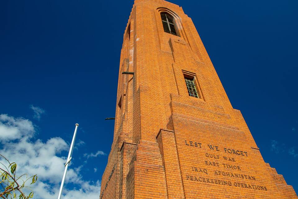 Una torre de maó alta amb inscripcions sobre conflictes militars i operacions de pau.