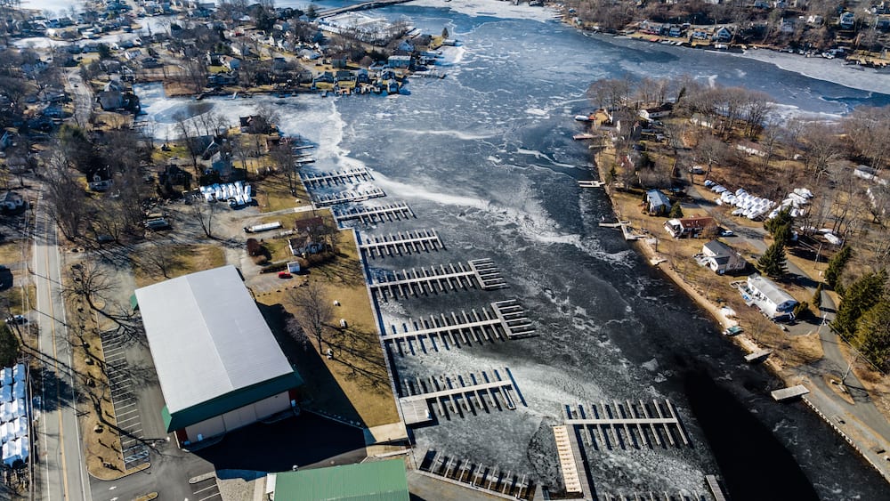 An aerial view of a frozen river with a marina and residential area.