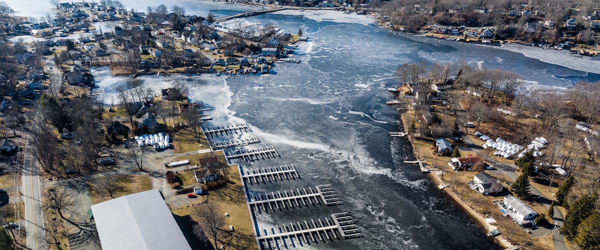 An aerial view of a frozen river with a marina and residential area.