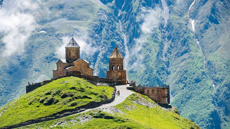 A historic church on a hilltop with a mountain backdrop.