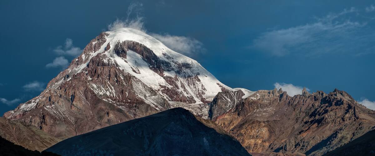 A snow-capped mountain with rugged terrain and a clear blue sky.