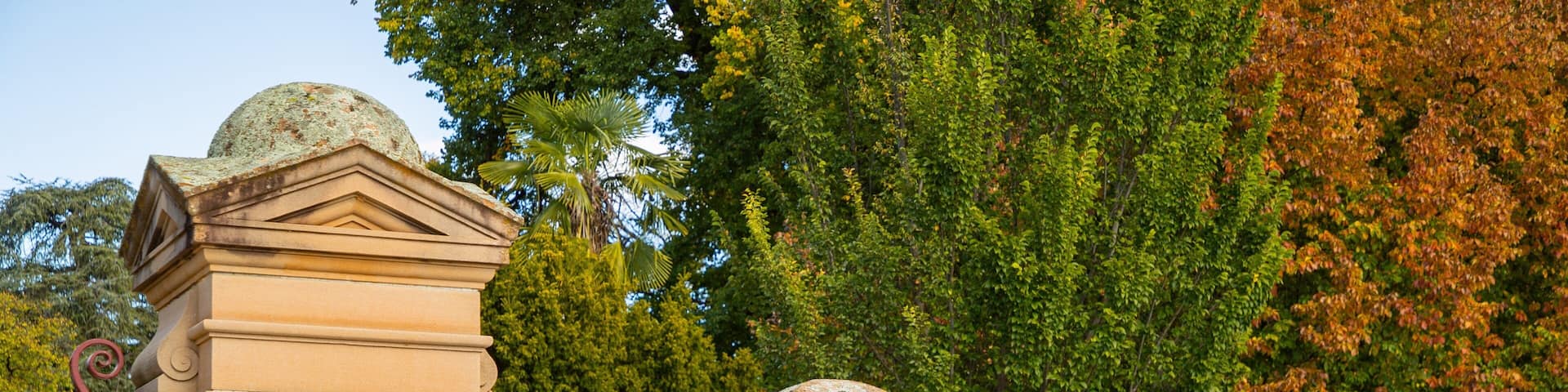 A stone monument with inscriptions, surrounded by lush greenery and trees.
