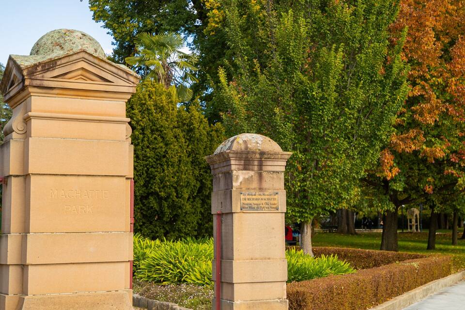 Een stenen monument met inscripties, omgeven door weelderige begroeiing en bomen.