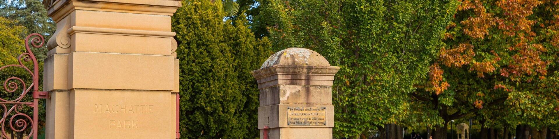 Monumento de piedra con inscripciones, rodeado de vegetación exuberante y árboles.