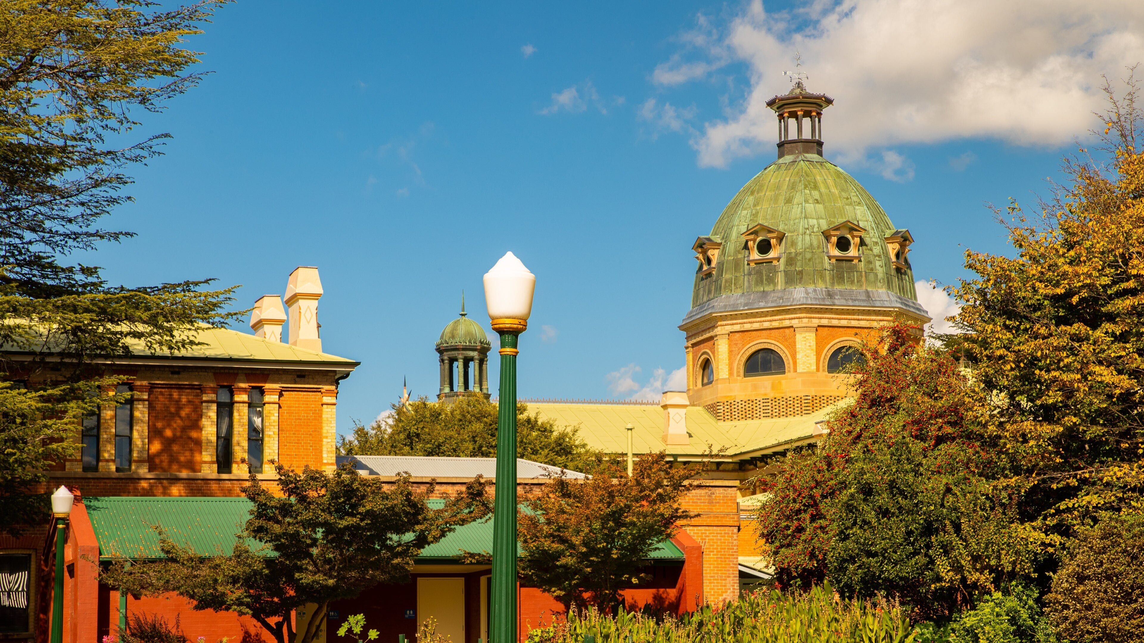 Um edifício histórico com uma cúpula verde e fachada de tijolos vermelhos.