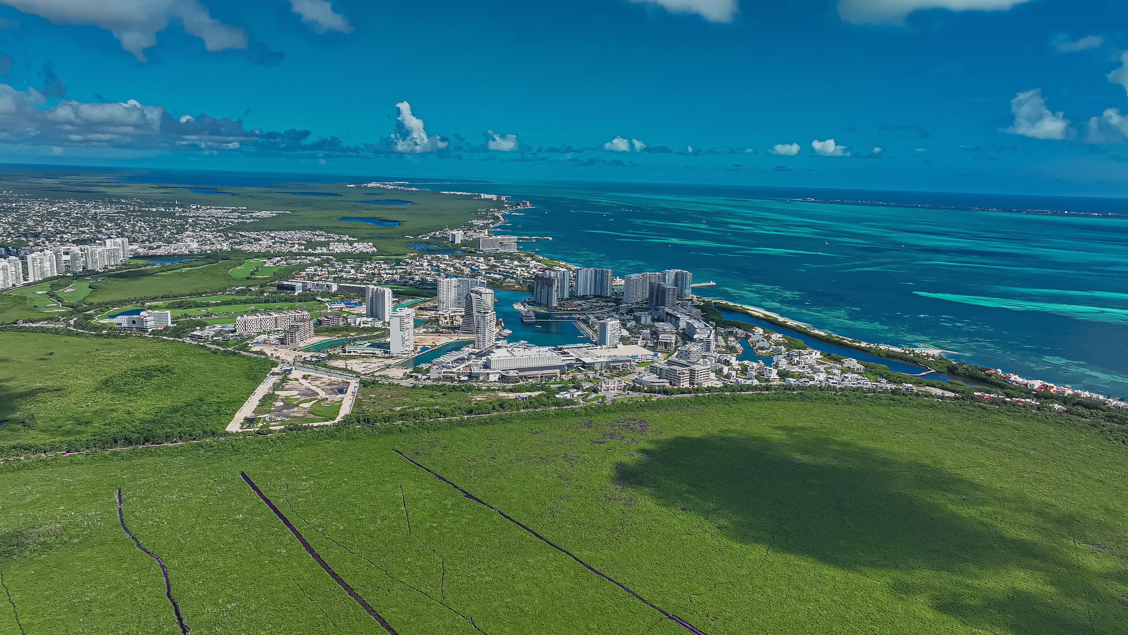 A coastal city with high-rise buildings, a marina, and a large green area.