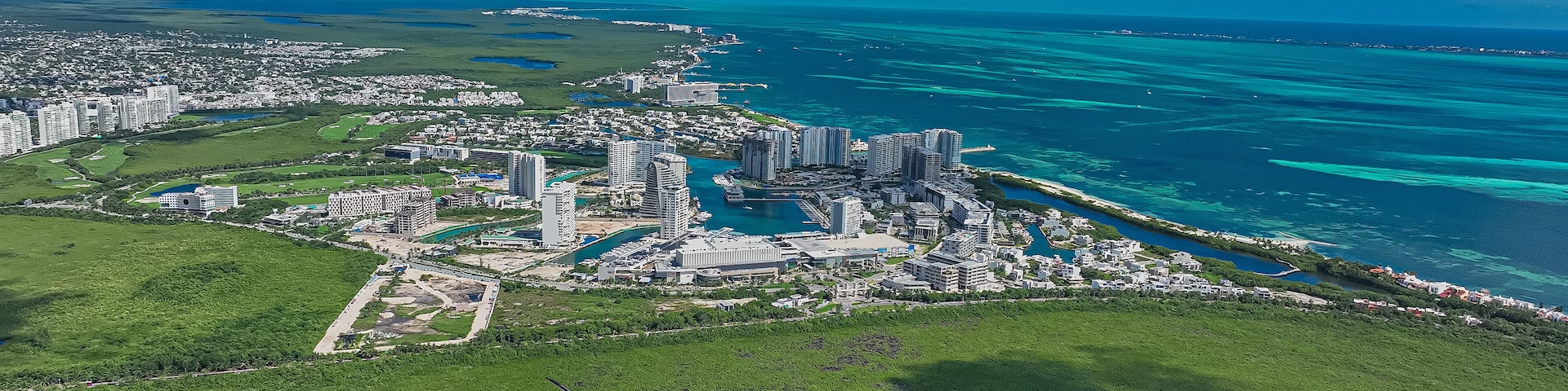 A coastal city with high-rise buildings, a marina, and a large green area.