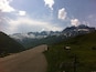 Une route de montagne avec des sommets enneigés en arrière-plan.