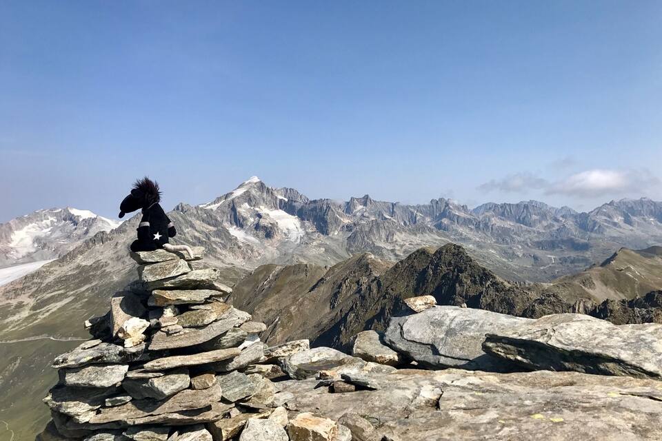 Una persona vestida de caballo sentada sobre un montículo de piedras con una cordillera al fondo.