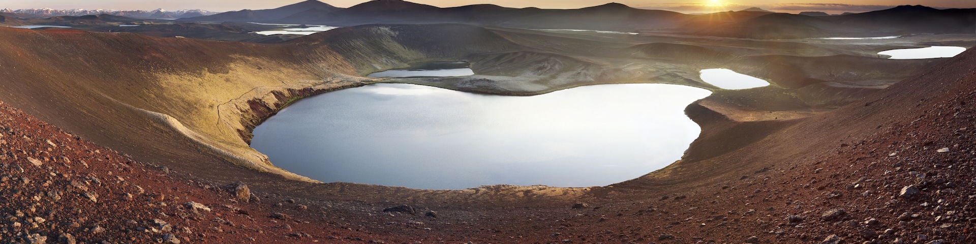 A large crater with a lake surrounded by mountains.