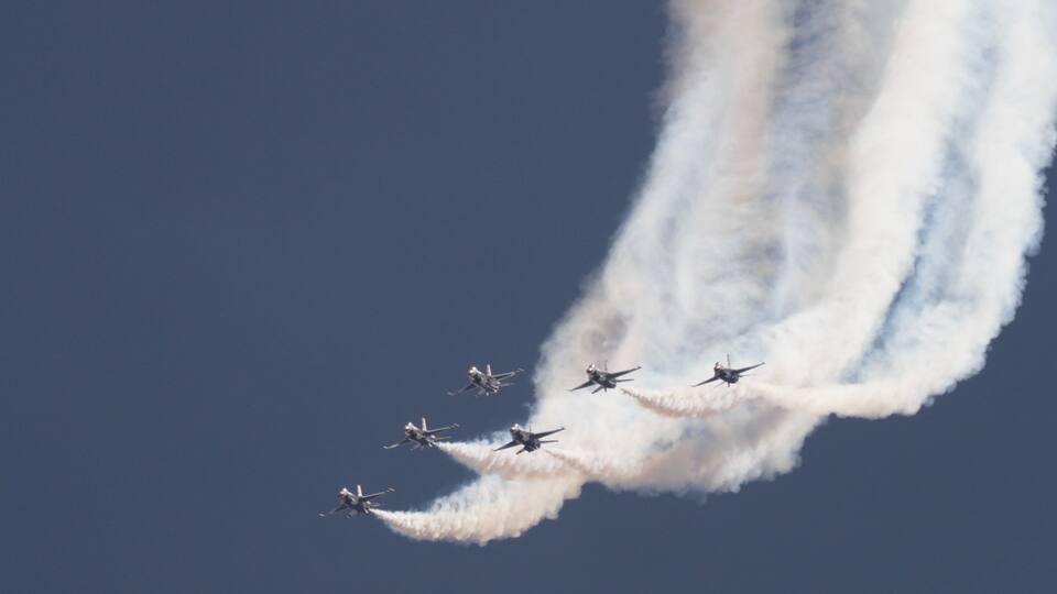 A group of jets flying in formation with smoke trails.
