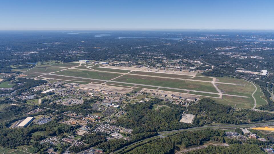 An aerial view of a large airport with multiple runways and surrounding urban and rural areas.