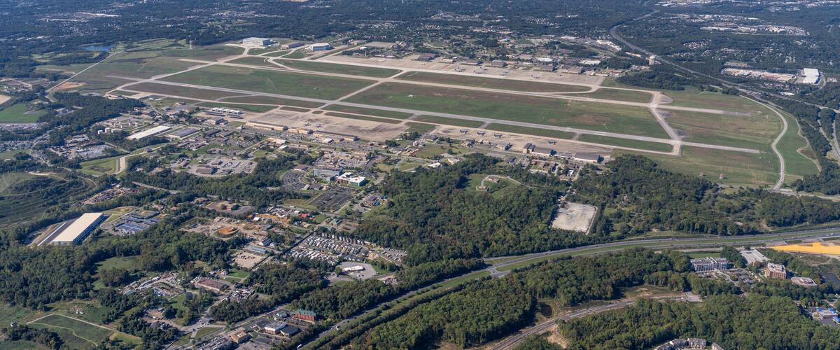 An aerial view of a large airport with multiple runways and surrounding urban and rural areas.