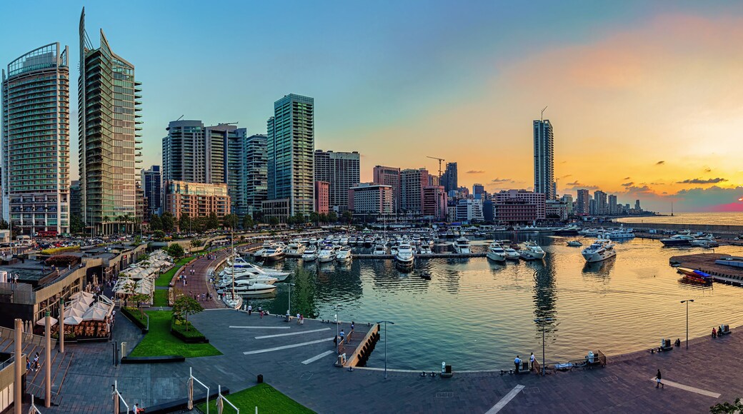 A panoramic photo of Beirut, Lebanon city skyline at sunset, featuring a marina with boats and a scenic waterfront walk.