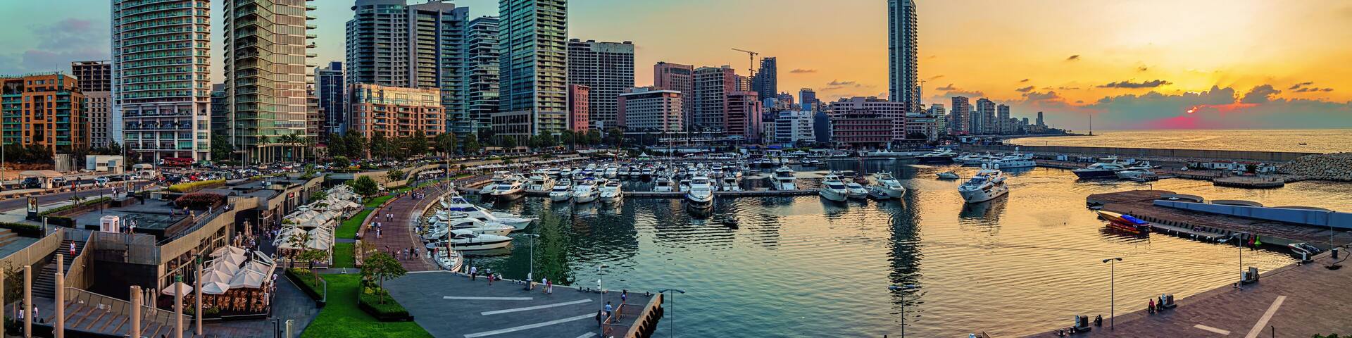 A panoramic photo of Beirut, Lebanon city skyline at sunset, featuring a marina with boats and a scenic waterfront walk.