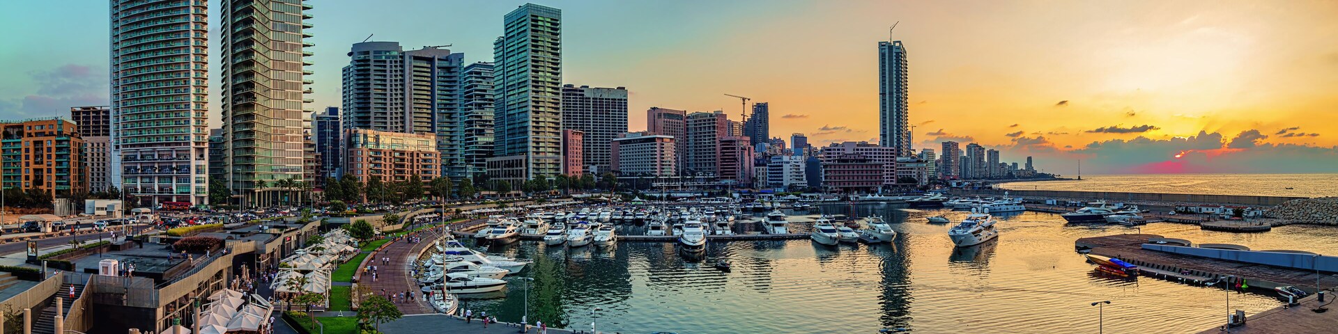 A panoramic photo of Beirut, Lebanon city skyline at sunset, featuring a marina with boats and a scenic waterfront walk.