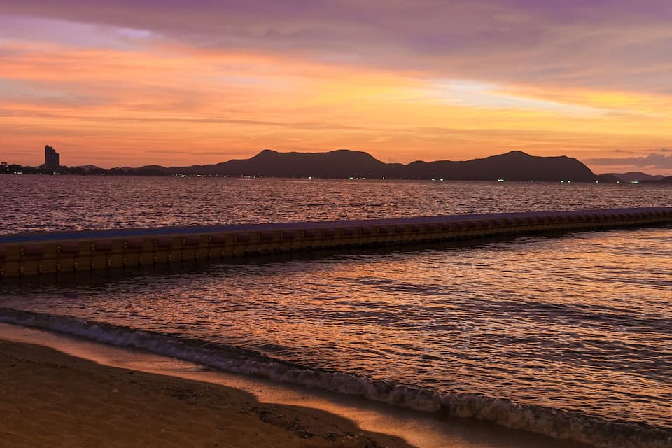 Un tramuntana sobre una platja amb un passeig marítim i edificis al fons.