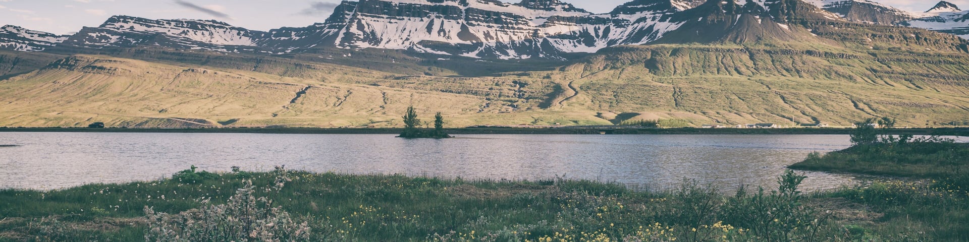 A lake surrounded by mountains with snow-capped peaks and a clear sky.