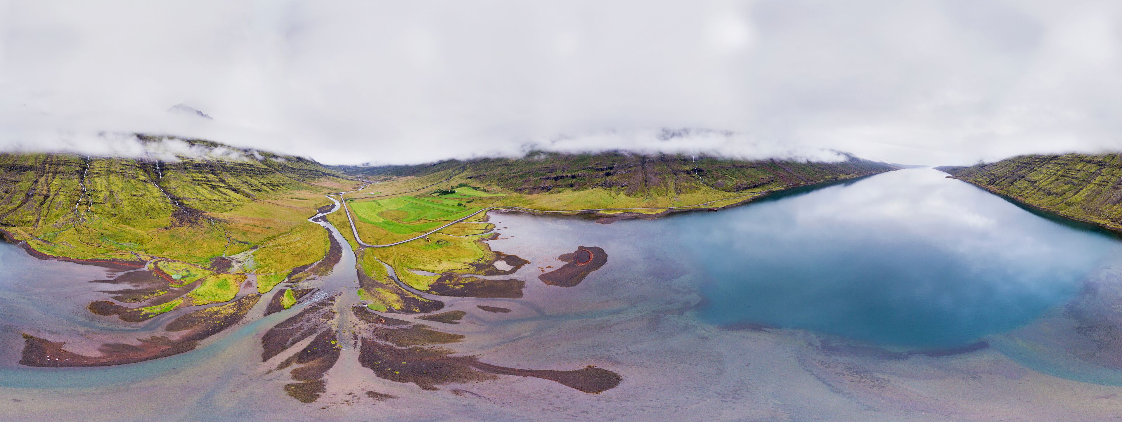 A river winding through a green valley with a lake on the right.