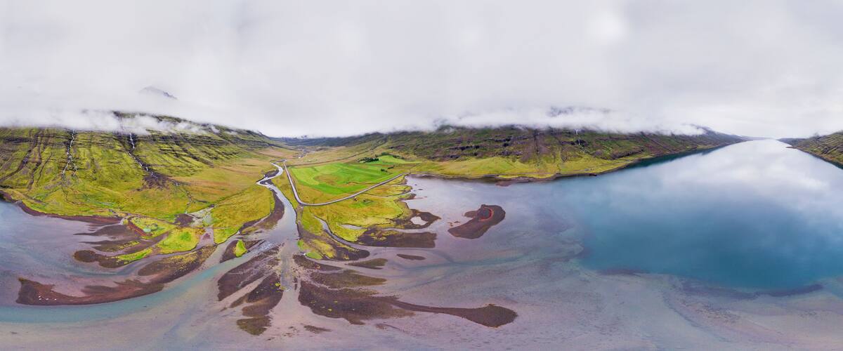 A river winding through a green valley with a lake on the right.