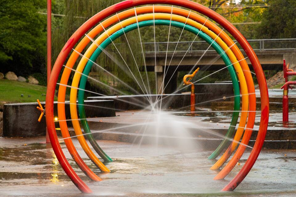 A colorful water fountain with a rainbow arch structure.
