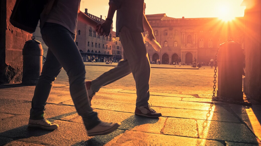 Couple walking in the city at sunset. Piazza Santo Stefano - Bologna, Italy.
