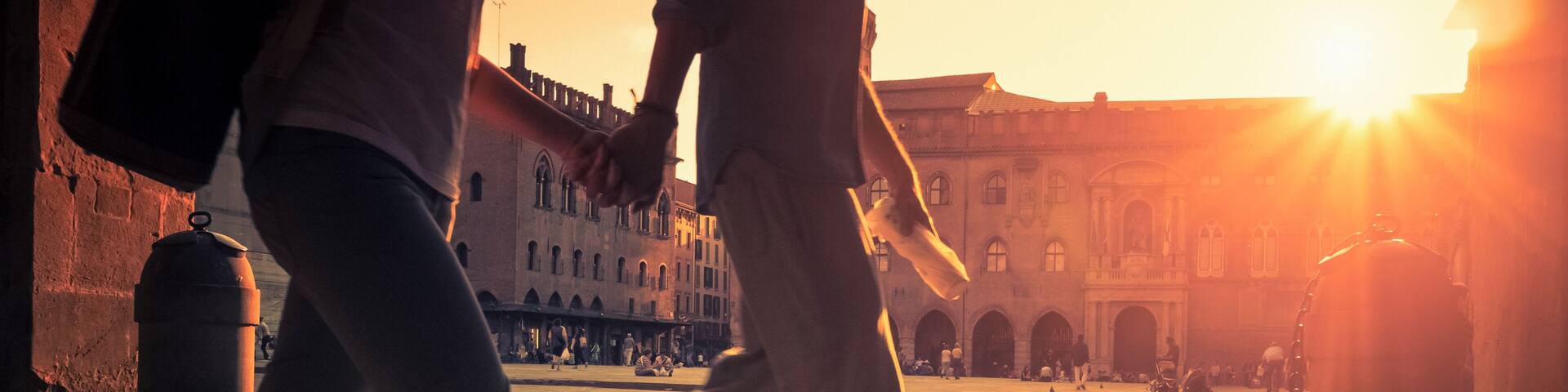 Two people walking on a cobblestone street with a sunset in the background.