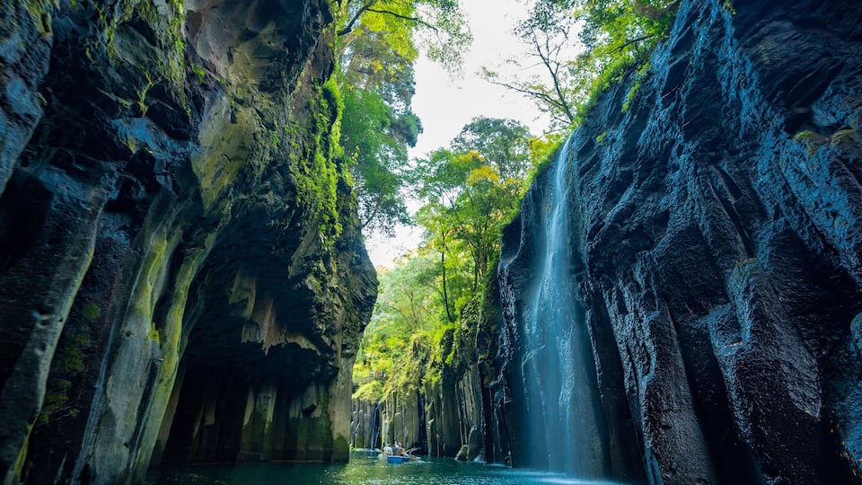 A waterfall cascading down a rocky cliff surrounded by lush greenery.