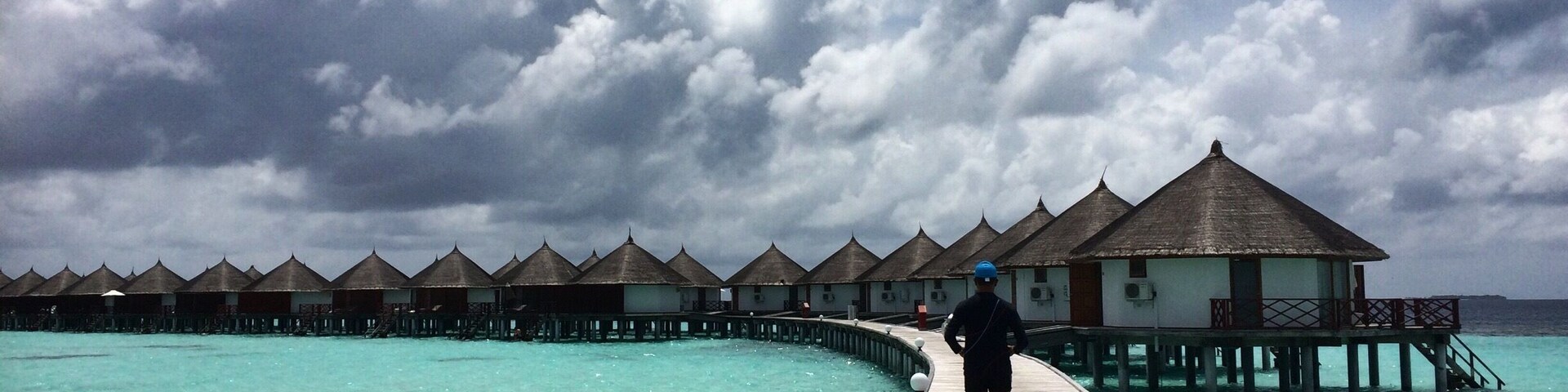 Un muelle de madera que lleva a bungalows sobre el agua, con un mar turquesa transparente.