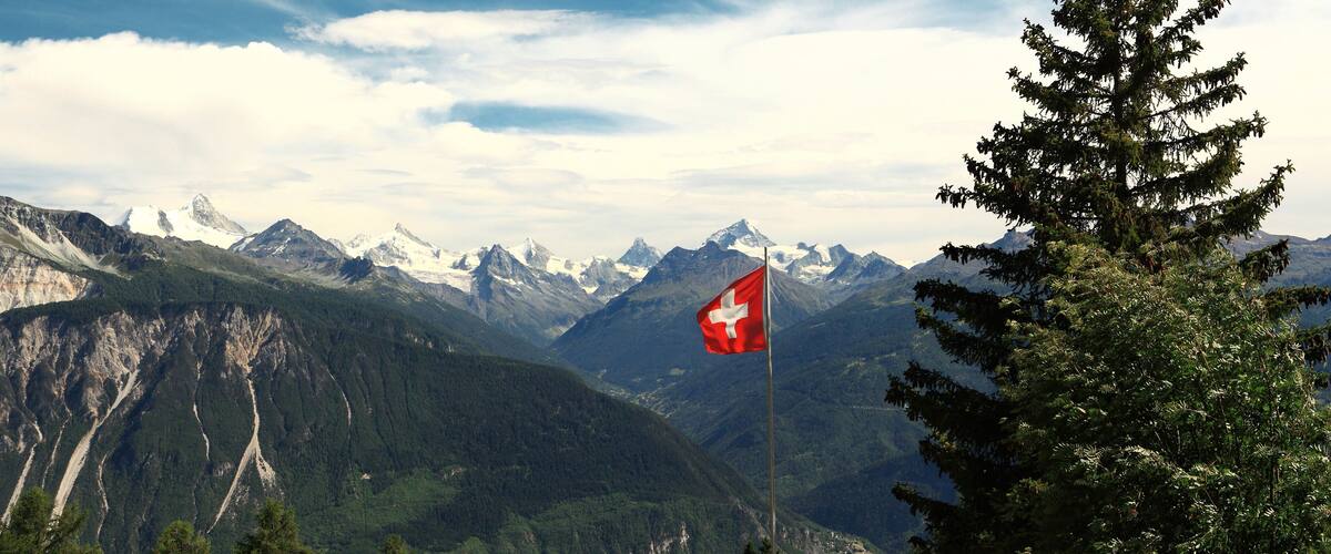 A mountainous landscape with a Swiss flag.
