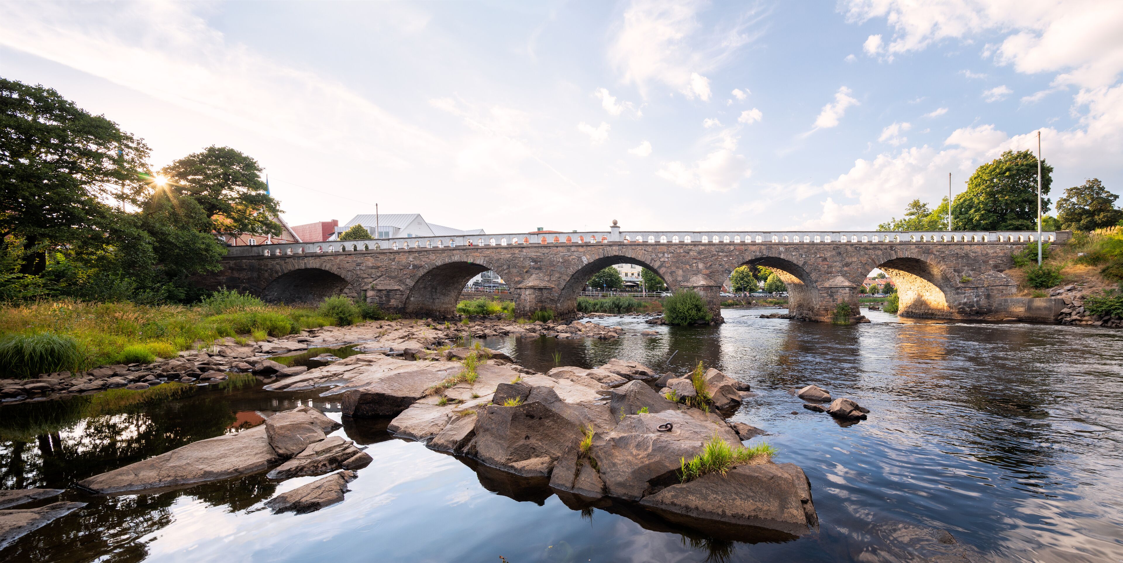 A stone bridge over a river with rocks in the foreground.