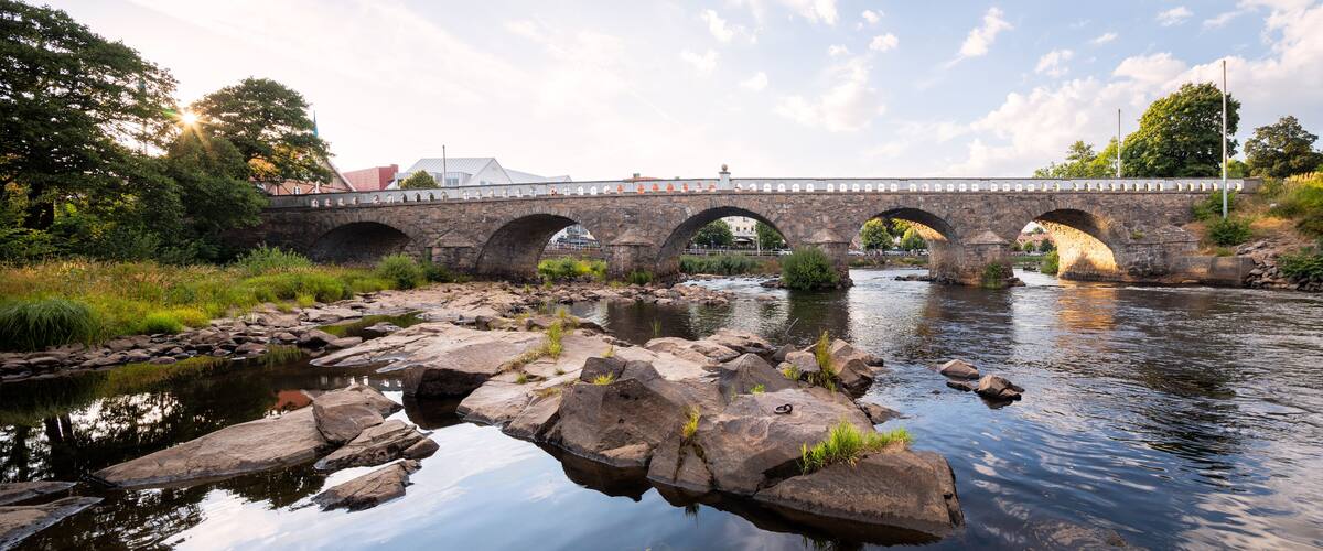 A stone bridge over a river with rocks in the foreground.