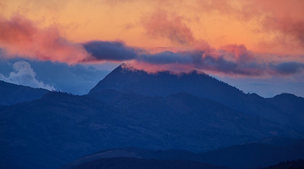 A view of the Costa Rican volcano in the clouds, lit by the setting sun. Quetzal forest after sunset. Los Quetzales National Park Nature Reserve. Costa rica.