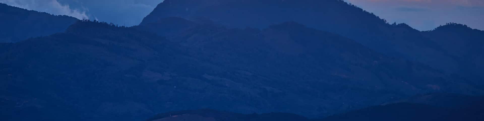 A view of the Costa Rican volcano in the clouds, lit by the setting sun. Quetzal forest after sunset. Los Quetzales National Park Nature Reserve. Costa rica.