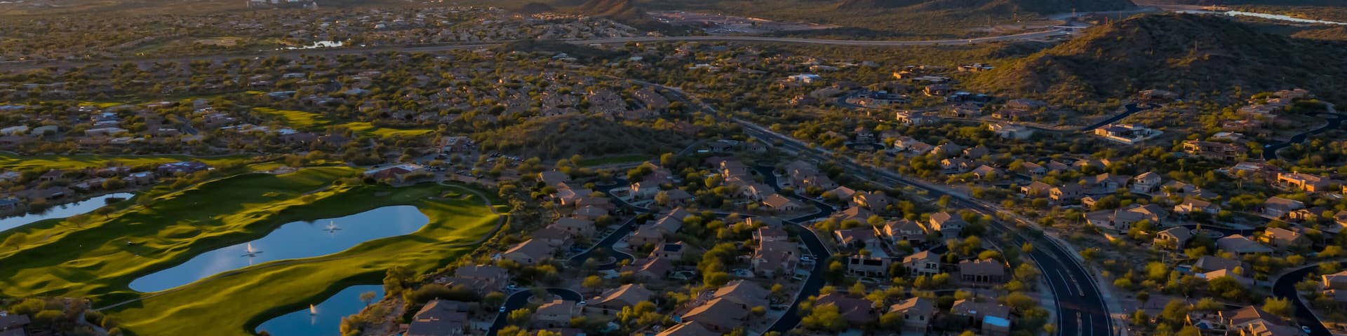 An aerial view of a suburban area with houses, roads, and a large body of water.